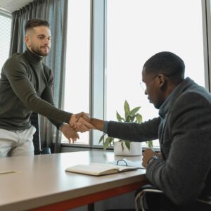 Two businessmen shaking hands in a modern office after a successful meeting or interview.